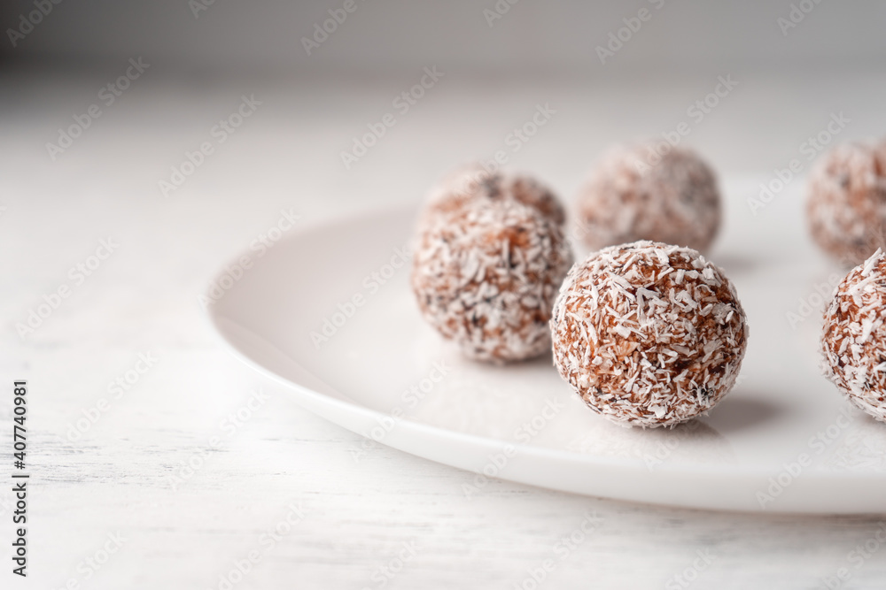 Date candy with coconut shavings on a flat white plate close-up Date candy with coconut shavings on a flat white plate close-up