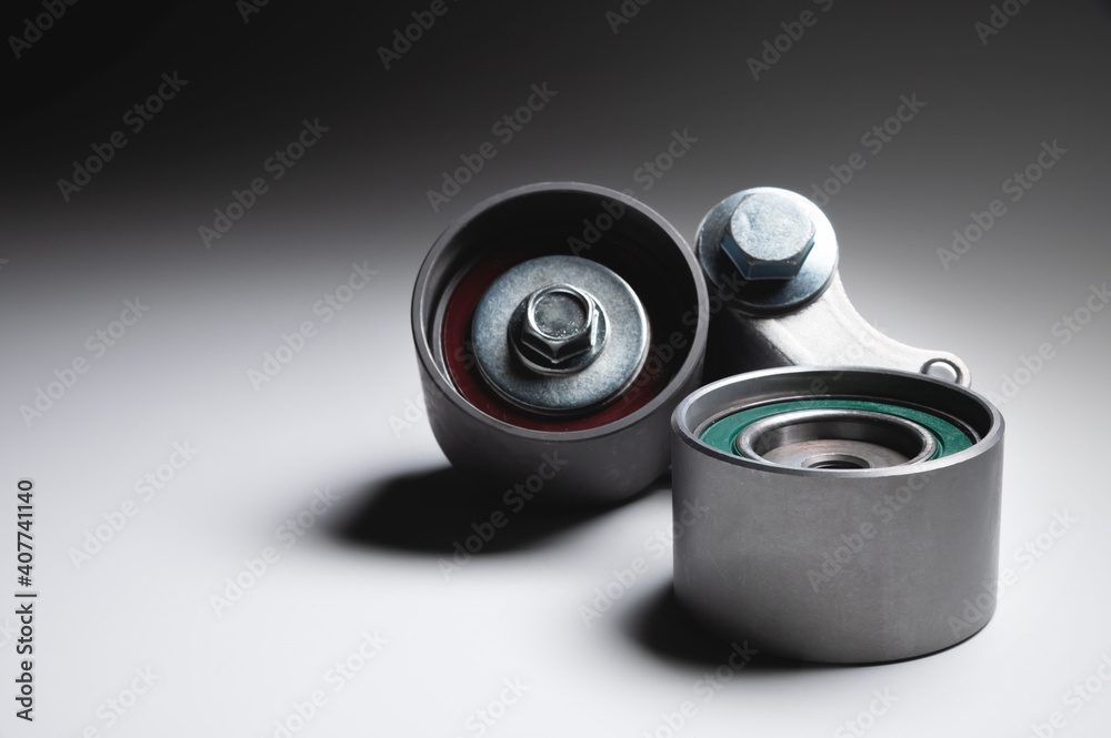 Two tensioning rollers of the engine timing belt on a gray background. New spare parts for car engine repair Two tensioning rollers of the engine timing belt on a gray background. New spare parts for car engine repair