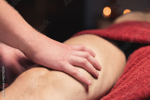 Close-up of professional knee and hip massage. Male masseur doing massage to male client