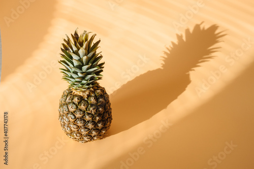 Pineapple with hard trendy shadow on pastel yellow background.