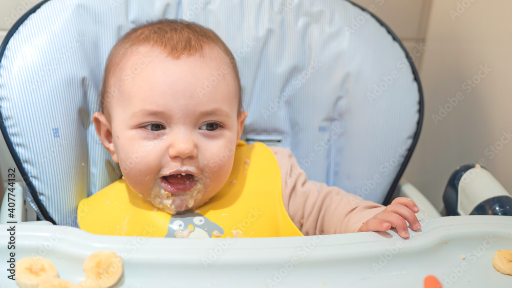 Cute baby girl eating porridge starting on solid food for the first time. 6 month old baby developmental milestone.