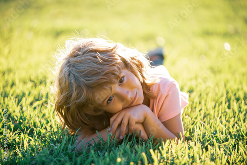 Children adaptation. Child in park outdoor. Spring kid lying on grass. Summer boy walk.