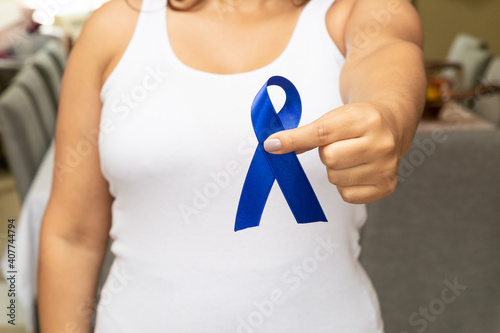 Young woman, with pink t-shirt, holding blue ribbon, preventing