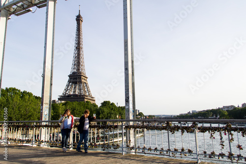 niño y niña en puente con candados de enamorados y vistas de la torre eiffel