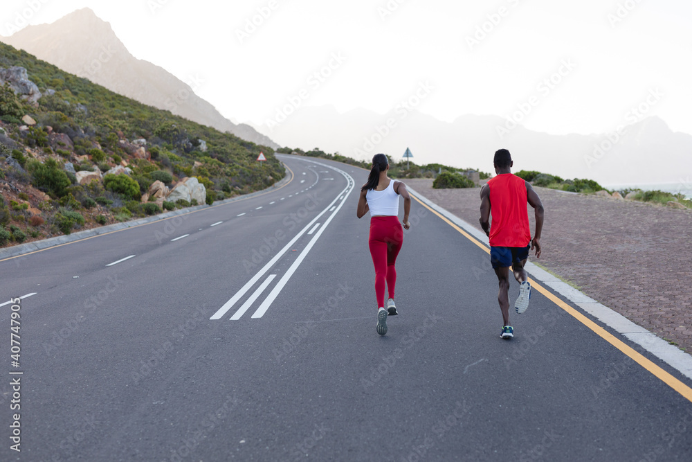 Fit african american couple in sportswear running on a coastal road Fit african american couple in sportswear running on a coastal road