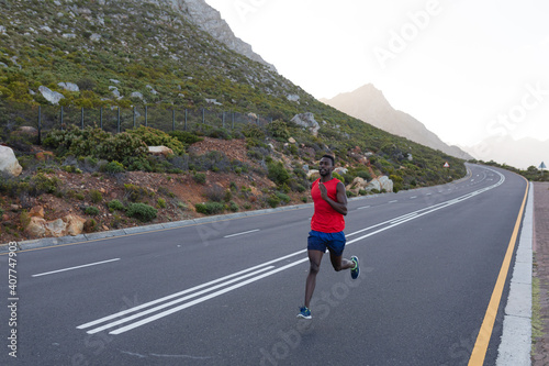 Fit african american man in sportswear running on a coastal road