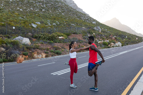 Fit african american couple in sportswear stretching on a coastal road