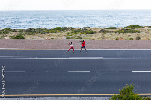 Fit african american couple in sportswear stretching on a coastal road