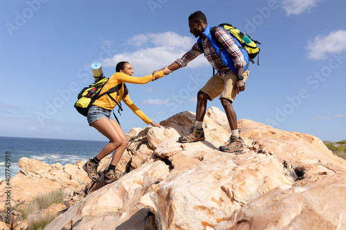 Fit afrcan american couple wearing backpacks hiking on the coast photo