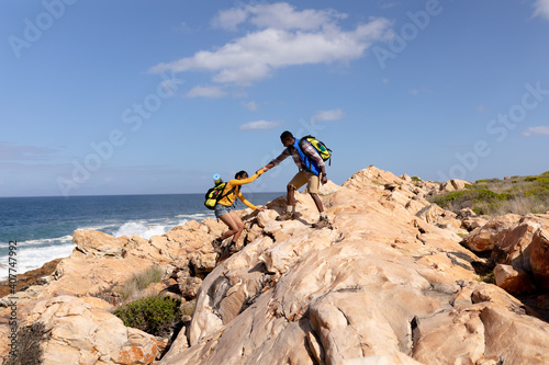 Fit afrcan american couple wearing backpacks hiking on the coast