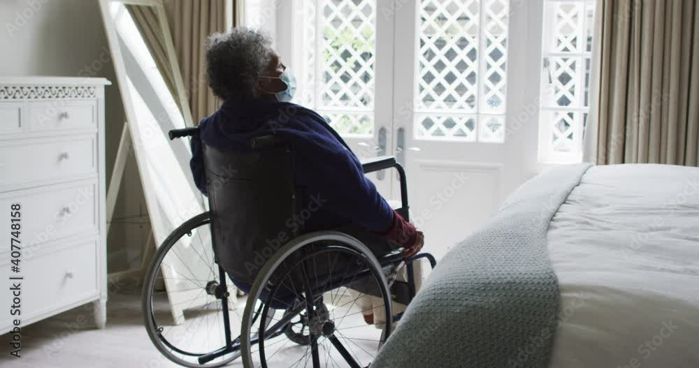 Senior african american woman wearing face mask sitting on the wheelchair at home