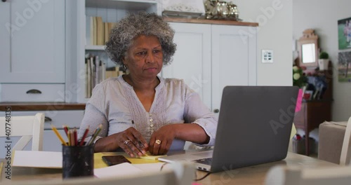 Senior african american woman sticking memo notes on her laptop at home photo