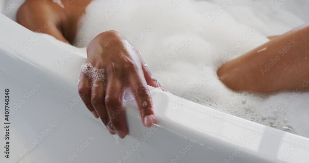 Close up of african american woman relaxing in the bath tub in the bathroom at home
