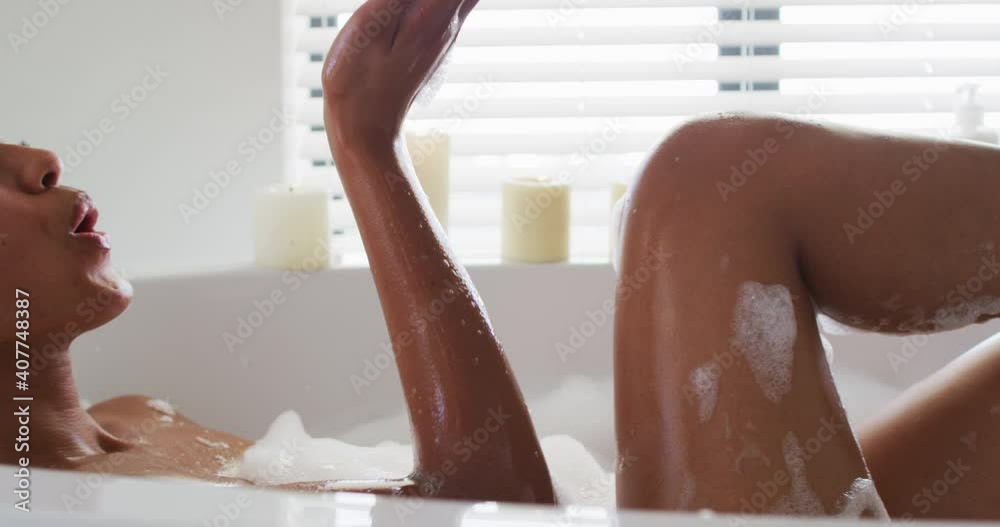 Close up of african american woman blowing soap bubbles in the bath tub in the bathroom at home