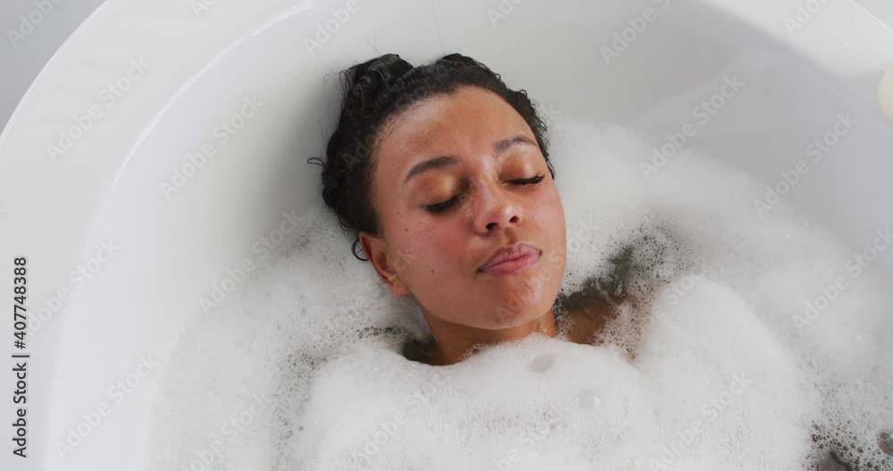 African american woman relaxing in the bath tub in the bathroom at home