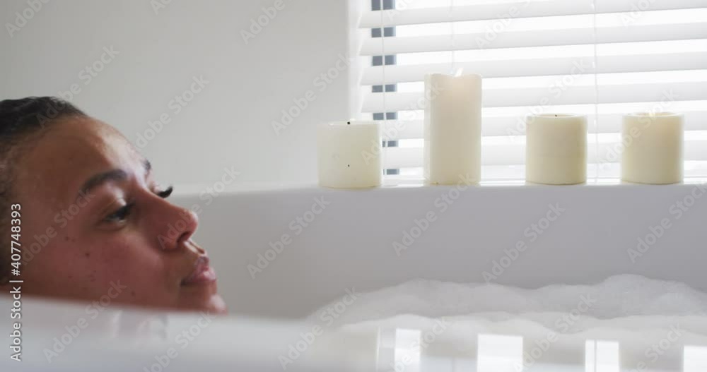 African american woman relaxing in the bath tub in the bathroom at home