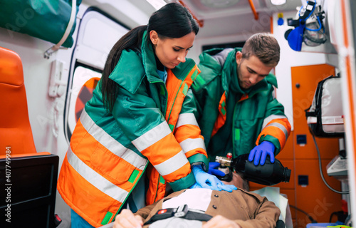 Unconscious senior man and working paramedics in the ambulance