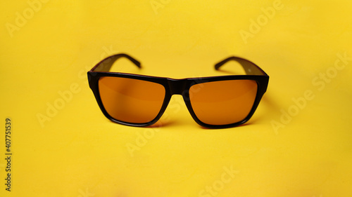Close up of sunglasses on yellow background. Fashionable accessory for protection eyes from sun.