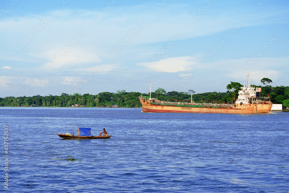 Obraz premium Small boats and cargo ships are going on the Kirtankhola river