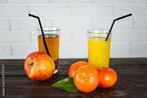 a glass of apple and orange juice with apples and oranges on the table