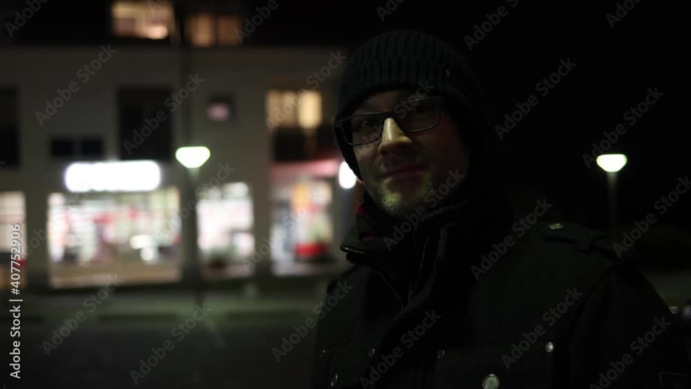 Junger Mann im Dunklen vor beleuchteten Gebäude