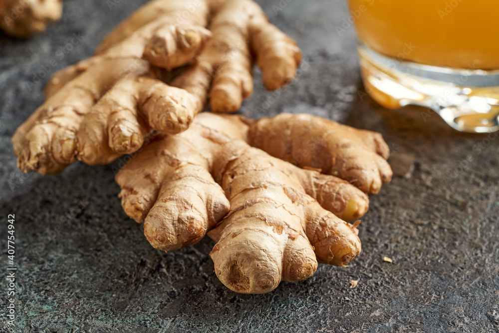 Fresh ginger root, with a probiotic ginger drink in the background