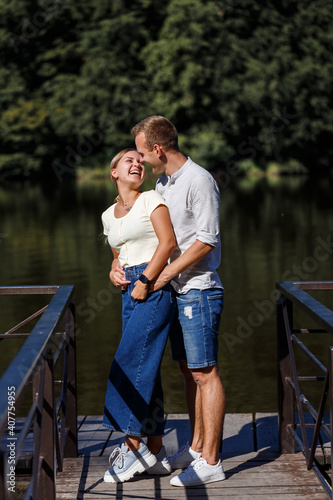 A beautiful loving young couple stands on the bank of the river they hug. Happy married couple on vacation by the lake