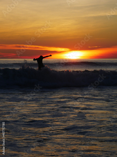 sunset on the beach, surfer on the ocean playing with waves
