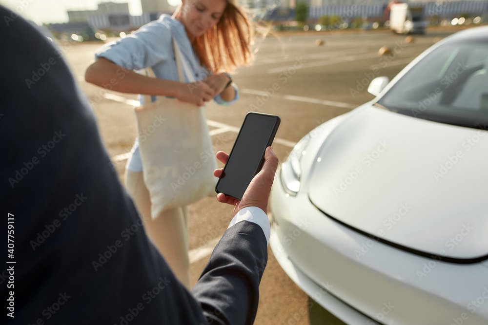 Man using smartphone for car hood opening Man using smartphone for car hood opening