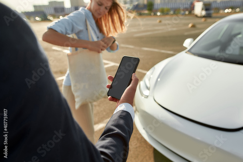 Man using smartphone for car hood opening