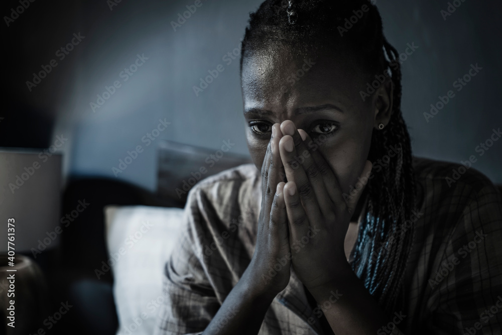 dramatic home portrait of young sick and depressed black African American girl sitting on bed upset and sleepless at night feeling overwhelmed suffering depression and anxiety problem dramatic home portrait of young sick and depressed black African American girl sitting on bed upset and sleepless at night feeling overwhelmed suffering depression and anxiety problem