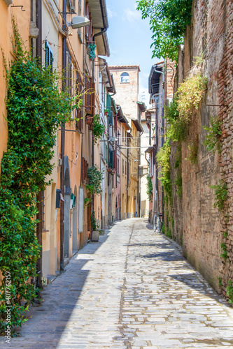 Fototapeta Naklejka Na Ścianę i Meble -  Vertical shot of an alley among stone buildings with green plants