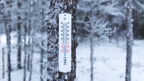 Thermometer on a background of winter forest shows 5 degrees below zero. Cold weather concept.