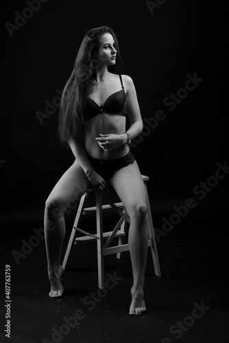 Portrait of brunette girl in underwear standing in the studio with black background.