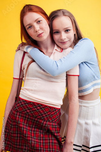 ifestyle people concept: two pretty young school teenage girls having fun happy smiling on yellow background photo