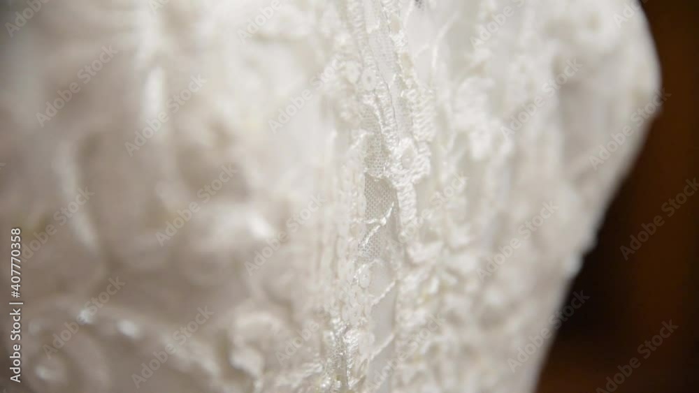 White wedding dress illuminated with light from a window. Lace and sewing of a wedding dress. White wedding dress illuminated with light from a window. Lace and sewing of a wedding dress.