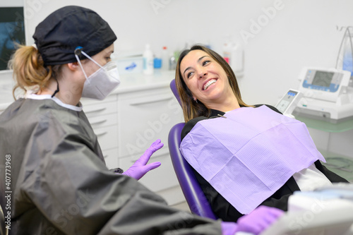 Young female patient visiting dentist office.Beautiful woman sitting at dental chair with open mouth during oral checkup while doctor working at teeth. High quality photo