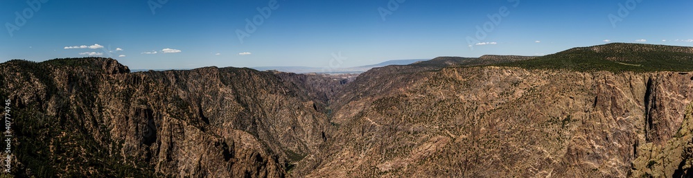 Panorama shot of gunnison river and rocky walls in black canyon of gunnison at sunny day in america