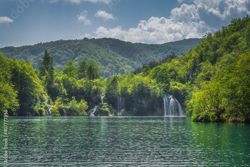 Turquoise lake and waterfalls illuminated by sunlight with forest covering green hills  Plitvice Lakes National Park UNESCO World Heritage  Croatia
