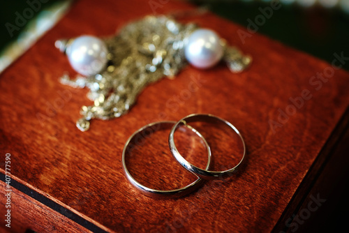 silver wedding rings in a wooden box decorated with pearls. vintage background photo