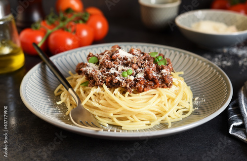Spaghetti with bolognese sauce  basil and parmesan on a dark concrete background.