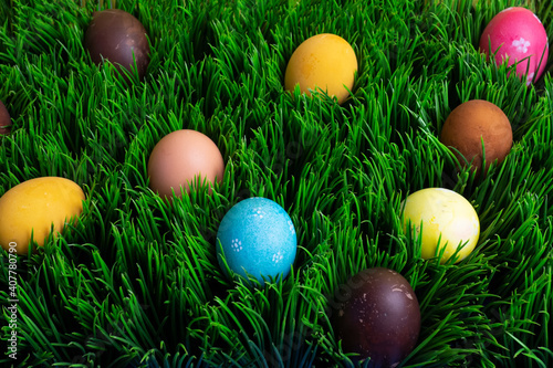 Many colorful painted Easter eggs in grass flat lay.