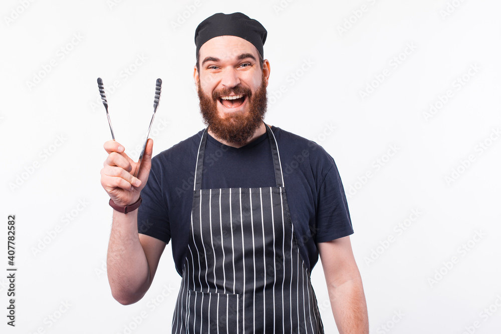 Photo of happy chef man holding utensil for cooking meat. Photo of happy chef man holding utensil for cooking meat.