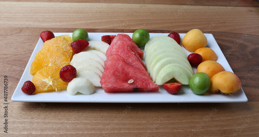 Mixed fruits plate, orange, watermelon, strawberries, apple, plum, apricot

