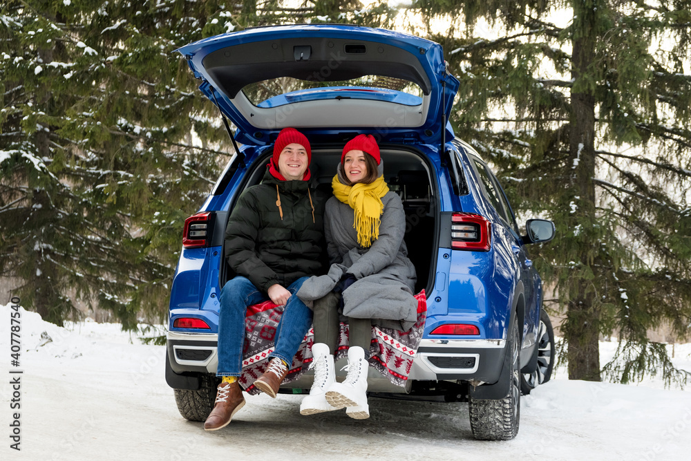 Romantic young hipster couple hugging while sitting in car trunk. Love, valentines and holiday concept. Kiss and hug. Valentines day celebration and happiness concept