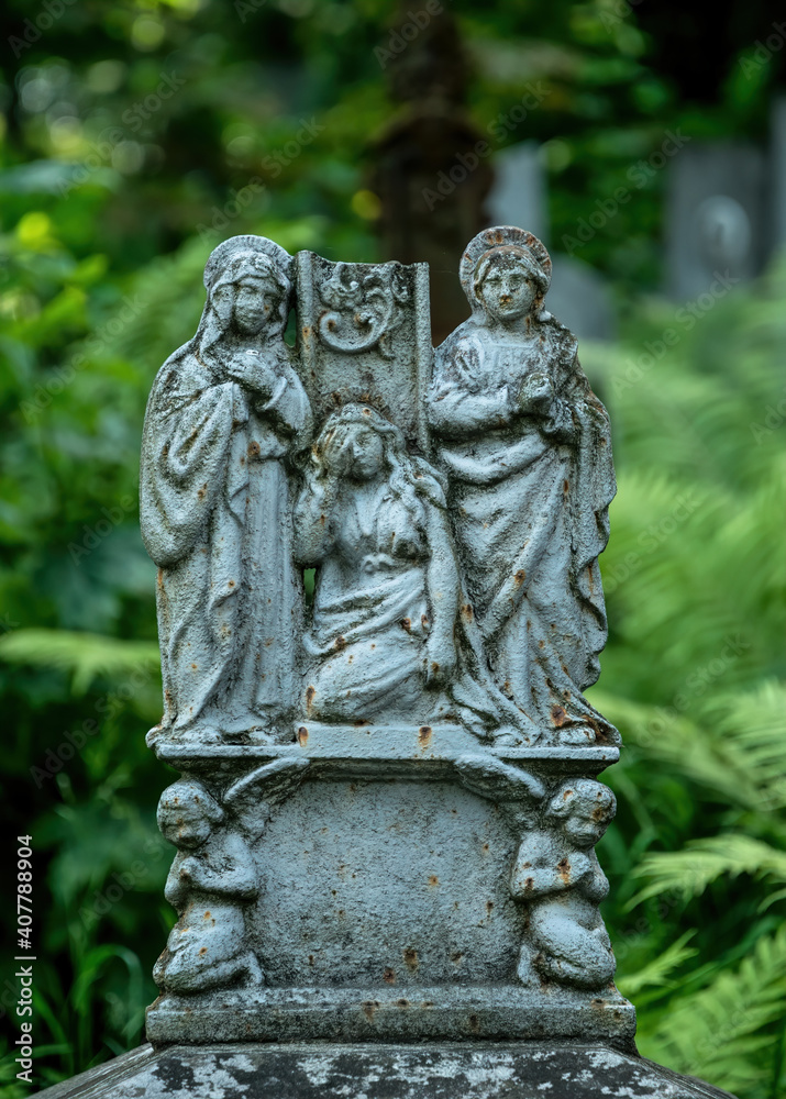 Lviv, Ukraine - July 12, 2019: Ancient gothic Lychakiv cemetery in Lviv, Ukraine. Ancient stone crypts, tombs and gravestones against the backdrop of overgrown green trees and herbs. Famous landmark