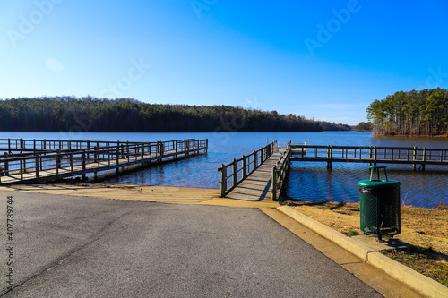 a majestic shot of the still blue lake waters of Lake McIntosh in Peachtree City, Georgia with lush green and autumn colored trees and grass with blue skies photo