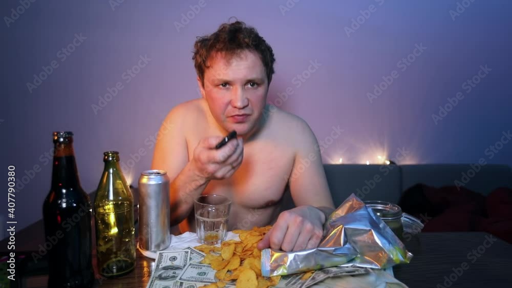 Redneck man watching TV laughs and eats chips