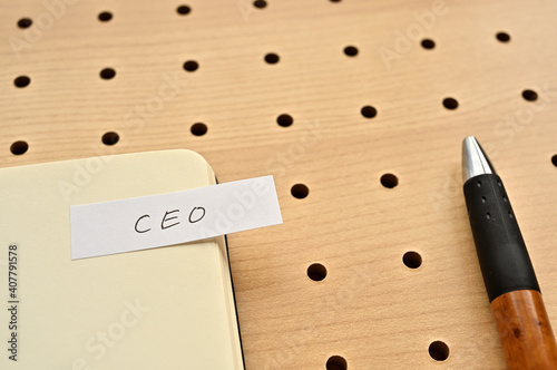 A sticky note with CEO written on the edge of an open notebook on the punching board. That's an acronym for Chief Executive Officer. photo