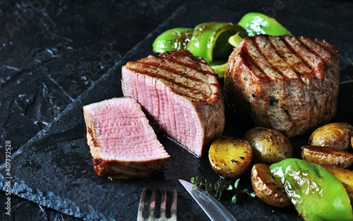 grill filet mignon and vegetables, grilled - young potatoes and peppers. steak mignon from the meat of young beef is shown in section, the degree of preparation is 